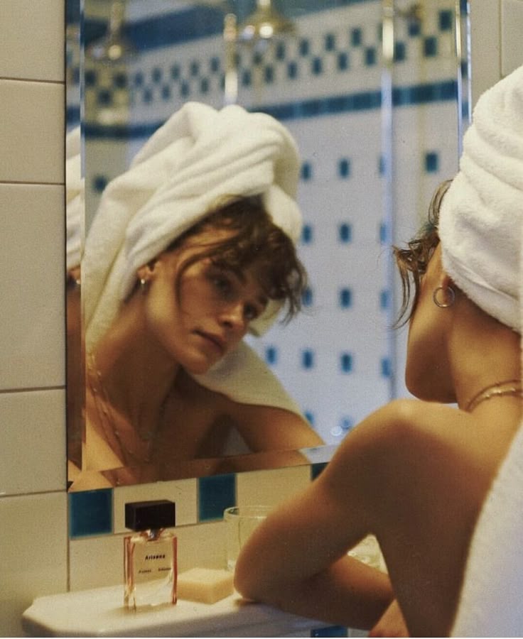 Woman wrapped in a towel reflected in a vintage bathroom mirror