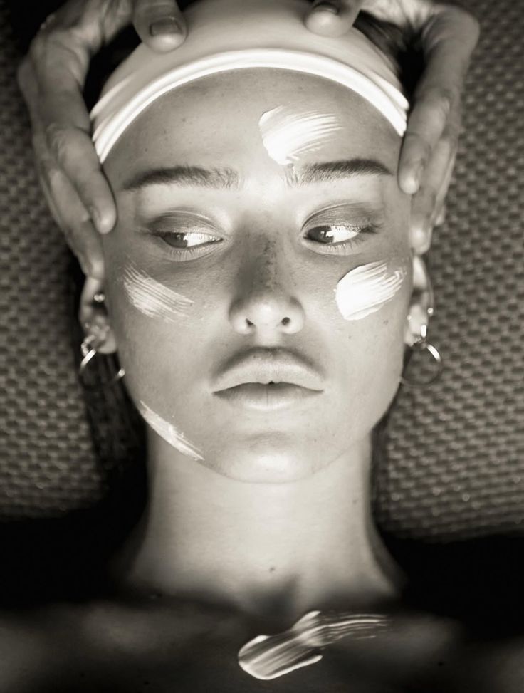 Black-and-white close-up of a woman applying facial cream